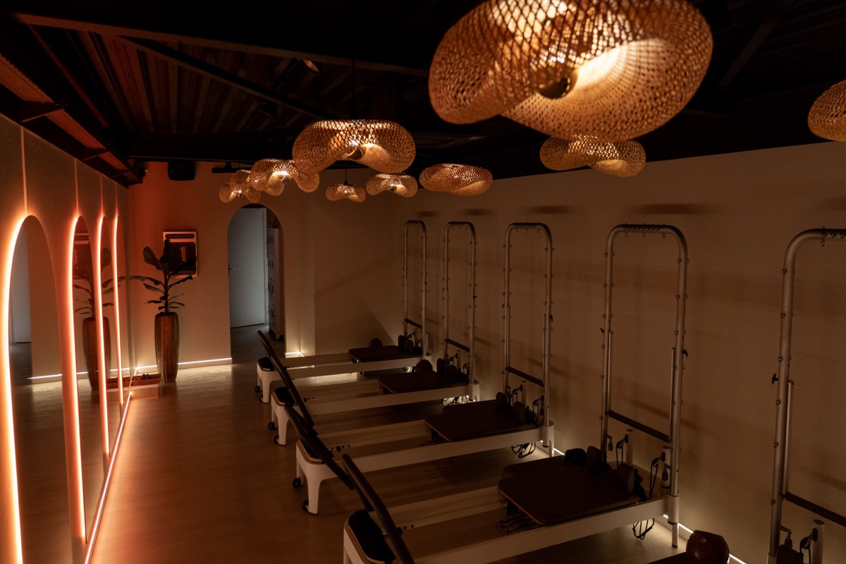 Reformer machines in de Refined Movement studio onder rattan plafondlampen met warme sfeerverlichting